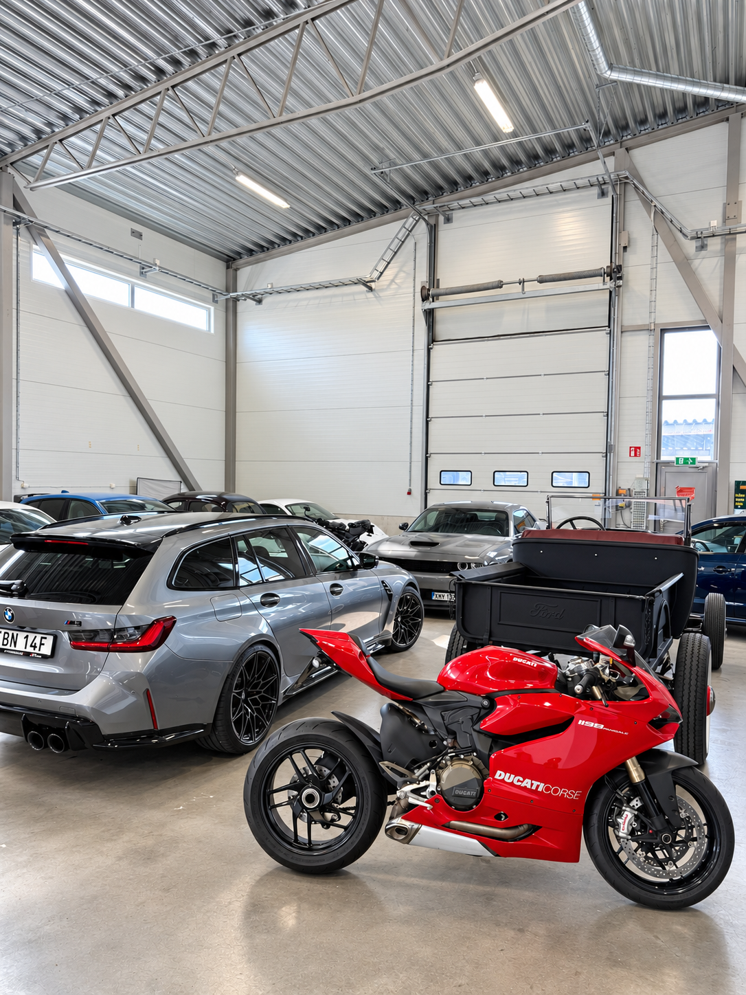 Bilar och motorcyklar i RT Motors lokal – BMW kombi, Dodge Challenger, Ford pickup och en röd Ducati