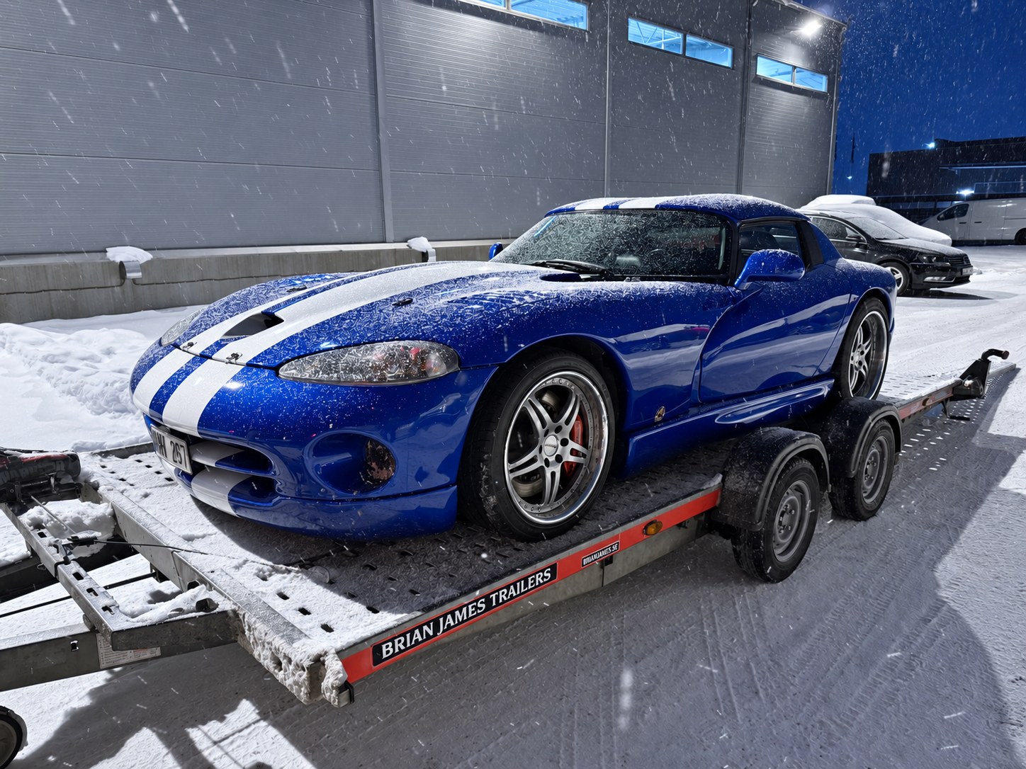 Blå Dodge Viper med vita racingränder på en trailer utanför RT Motors lokal i vinterskrud